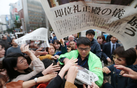 天皇陛下が即位を宣言されたことを知らせる号外に群がる人たち=22日午後、東京都中央区