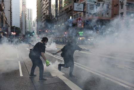 香港で警察が発射した催涙ガスが立ち込める中、抗議するデモ隊=2日(EPA時事)