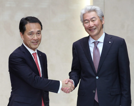 記者会見で握手する野村ホールディングスの新CEOに就任する奥田健太郎・共同COO(左)と会長に退く永井浩二CEO=2日午後、東京都中央区