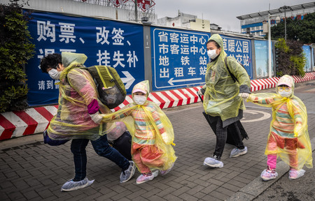 12日、中国・広州市の鉄道駅で新型コロナウイルスの感染を防ぐため体や足元を覆った乗客(EPA時事)