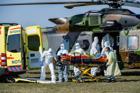 2日、ドイツ中部ノルトハウゼン近郊の空港で、新型コロナウイルスに感染したフランスの患者を運ぶ医療従事者(AFP時事)