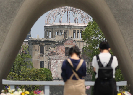 75回目の広島原爆の日を前に、原爆死没者慰霊碑に手を合わせる人たち。奥は原爆ドーム=5日午前、広島市中区