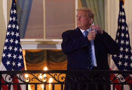 新型コロナウイルスから回復して退院した後、ホワイトハウスでマスクを外すトランプ前米大統領=2020年10月(AFP時事)