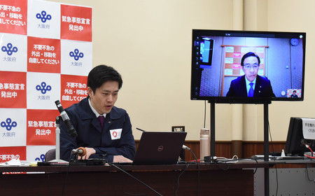 京都、兵庫両府県の知事とテレビ会議を行う大阪府の吉村洋文知事(左)=23日午後、大阪府庁