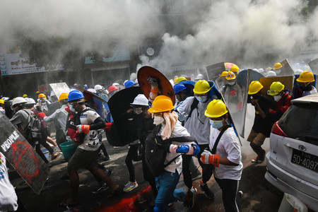 3日、ミャンマーの最大都市ヤンゴンで、盾を掲げて走る抗議デモの参加者ら(AFP時事)