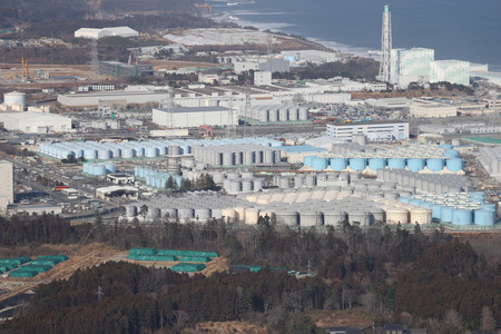 東京電力福島第1原発の敷地内に並んだ処理水を保管するタンク。右奥は5、6号機の原子炉建屋=2月14日、福島県上空(時事通信チャーター機より)