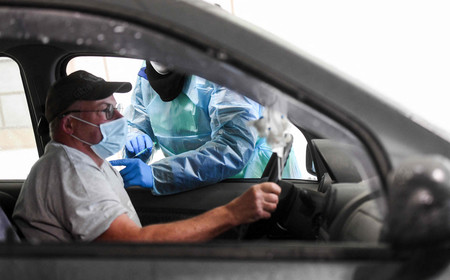 車の運転席に座ったまま、英製薬大手アストラゼネカの新型コロナウイルスワクチン接種を受ける男性=7日、ドイツ西部シュウェルム(AFP時事)