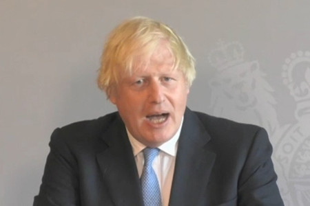 21日、ロンドンで、テレビ会議形式で英下院の質疑に臨むジョンソン首相=議会中継映像より(AFP時事)