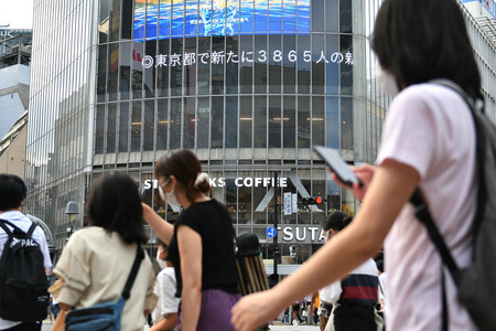 緊急事態宣言が発令される中、渋谷のスクランブル交差点を行き交う人々=29日、東京都渋谷区