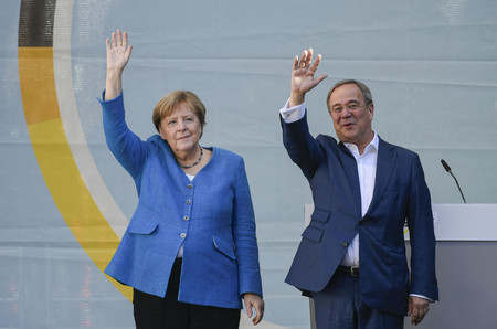 25日、ドイツ西部アーヘンで、支持者に手を振るメルケル首相(左)とキリスト教民主同盟(CDU)のラシェット党首(AFP時事)