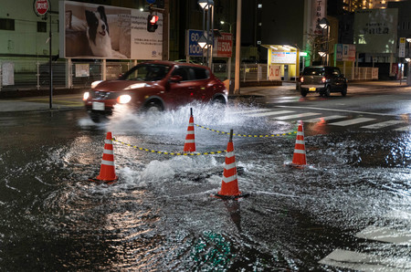地震の影響でマンホールから水があふれ、浸水した交差点=22日午前、大分市