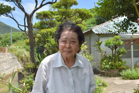 久部良の自宅前で話す長浜智恵子さん。嫁いできた1952年当時、自宅前の通りにも人があふれ、バーが並んでいたという=4月23日、沖縄県与那国町