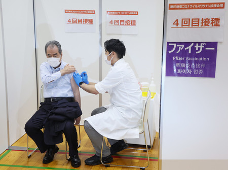 新型コロナウイルスワクチンの4回目接種を受ける人=25日午前、東京都港区