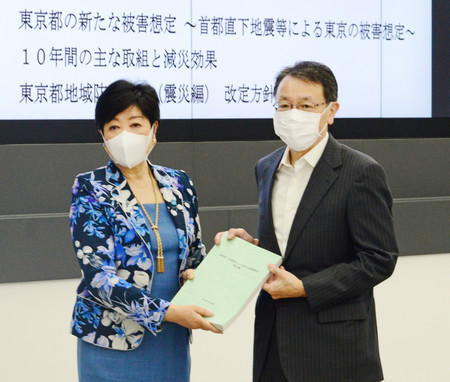 東京都防災会議の平田直部会長(右)から首都直下地震の新たな被害想定に関する報告書を受け取る小池百合子知事=25日午前、都庁
