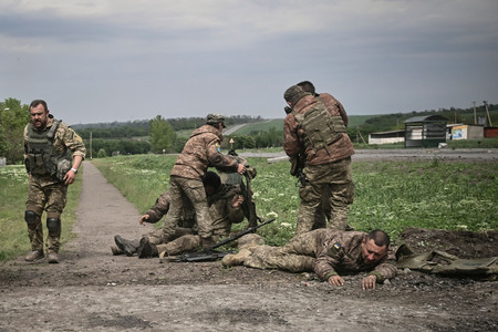 ウクライナ東部ドンバス地方の前線近くで、仲間を助けるウクライナ軍兵士=21日(AFP時事)
