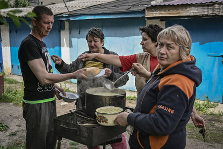 電気や水が止まり、屋外で食事の準備をするウクライナ東部の住民たち=26日、リシチャンシク(AFP時事)