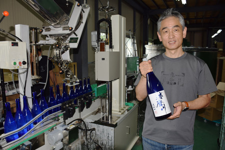 瓶詰めした「球磨川」を持つ下田文仁さん＝６月２３日、熊本県人吉市