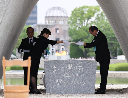 平和記念式典で、原爆死没者名簿を慰霊碑に納める広島市の松井一実市長(右)と遺族代表=6日午前、広島市中区