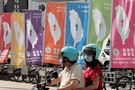 6日、台北市で、台湾独立を訴える旗の前を通り過ぎる市民(AFP時事)