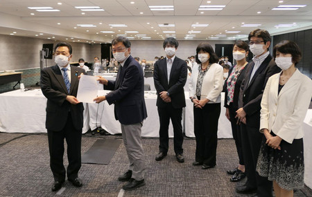佐藤英道厚生労働副大臣(左端)にマイナ保険証の報酬加算見直しを答申する中央社会保険医療協議会の小塩隆士会長(左から2人目)ら=10日、東京都千代田区(同省提供)