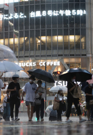強い雨の中、渋谷のスクランブル交差点を傘を差して歩く人たち=13日午後、東京都渋谷区