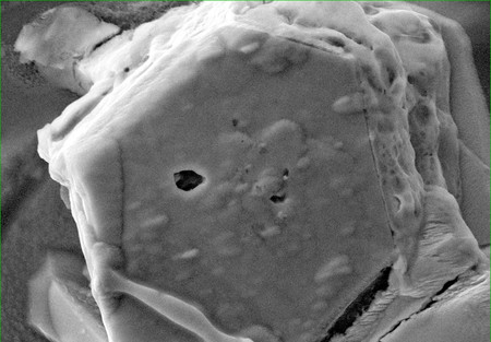 小惑星「りゅうぐう」の試料に含まれる硫化鉄結晶（六角形）。内部の穴（中央）から水が見つかった（ＮＡＳＡ／ＪＳＣ・東北大提供）