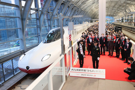 JR長崎駅を出発する西九州新幹線の始発列車。出発合図をするのは萱嶋創長崎駅長(手前右)と一日駅長の長濱ねるさん(同左)=23日午前、長崎市(代表撮影)