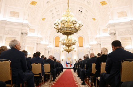 30日、モスクワのクレムリンで、ロシアのプーチン大統領の演説を聴く人々(EPA時事)