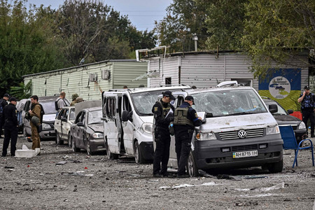 ウクライナ南部ザポロジエ市郊外で、ミサイル攻撃により損傷した車を調べる警察官＝９月３０日（ＡＦＰ時事）