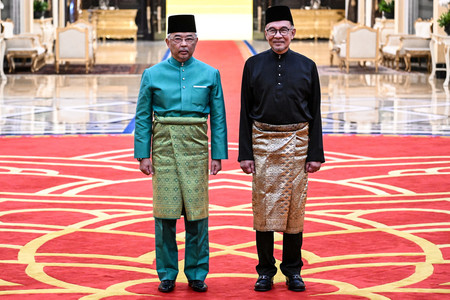 ２４日、マレーシアのクアラルンプールで、宣誓式に臨むアブドラ国王（左）とアンワル新首相（ＥＰＡ時事）