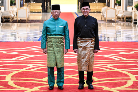 24日、マレーシアのクアラルンプールで、宣誓式に臨むアブドラ国王(左)とアンワル新首相(EPA時事)