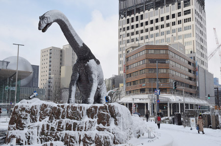 雪が積もったJR福井駅前にある恐竜のモニュメント=25日午前、福井市