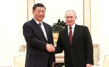 20日、モスクワで会談し、握手をする中国の習近平国家主席(左)とロシアのプーチン大統領(ロイター時事)