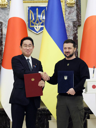 共同声明署名式で握手する岸田文雄首相（左）とウクライナのゼレンスキー大統領＝２１日午後、キーウ（内閣広報室提供）