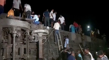 2日、インド東部オディシャ州バラソール地区で起きた列車衝突事故で横転した車両から脱出する人々(現場を撮影した動画より)(ロイター時事)