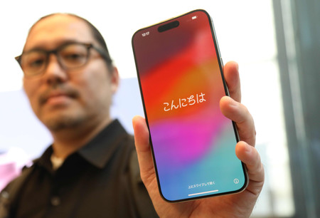 米アップルの新型スマートフォン「iPhone(アイフォーン)15」を手にする男性=22日午前、東京都渋谷区