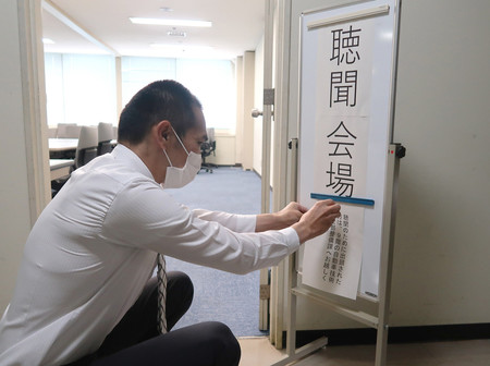ビッグモーターの聴聞会場に張り紙をする国土交通省中部運輸局職員=20日午前、名古屋市中区
