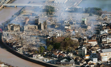 地震による火災が発生し、煙が上がる石川県輪島市の市街地＝２日午前（時事通信チャーター機より）