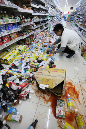 営業中の店舗で、地震により棚から落ちた商品を片付ける従業員＝２日午後、石川県七尾市
