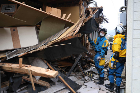 倒壊した家屋で行方不明者の捜索をする警察官＝５日午前、石川県輪島市