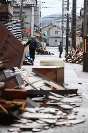 地震の影響によって崩れた家屋と道路に散乱しているがれき＝１０日、石川県輪島市