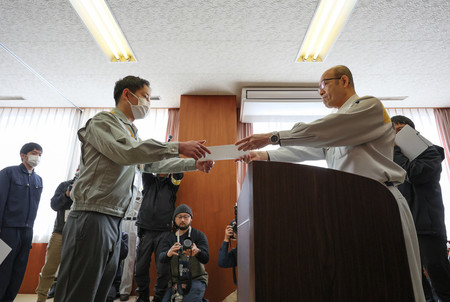 石川県輪島市の入庁式で、坂口茂市長（右）から辞令を受け取る新人職員＝１日午前、同市