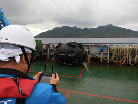 ドローンを操縦して魚釣島を撮影する調査員＝２７日午前、沖縄県石垣市の尖閣諸島沖