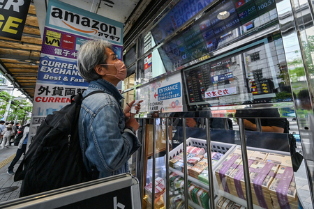 東京都内の両替店で、レートの表示を確かめる男性＝４月２９日（ＡＦＰ時事）
