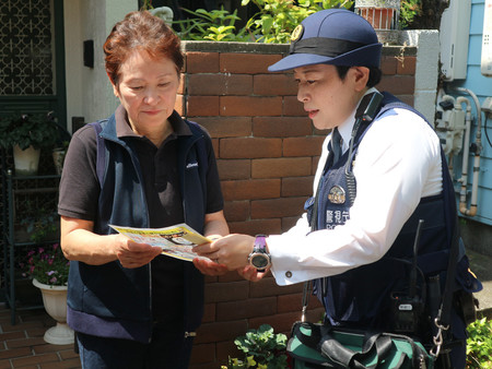 住人に悪質リフォーム業者への注意を呼び掛ける警視庁の警察官（右）＝４月２６日、東京都内