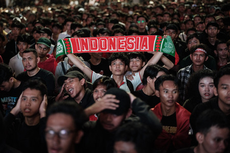 大型モニターの前で試合中継を見詰めるインドネシアのサッカーファン＝９日、ジャカルタ（ＡＦＰ時事）
