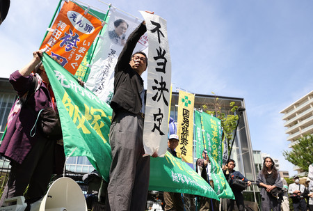 福岡地裁で飯塚事件の再審請求が棄却され、「不当決定」の紙を掲げる支援者ら＝５日午前、福岡市中央区