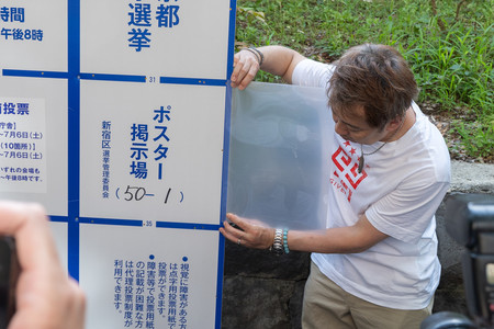 東京都知事選で立候補者多数のため枠が不足し、掲示板の外側にポスターを貼るためのクリアファイル＝２０日午後、東京都新宿区