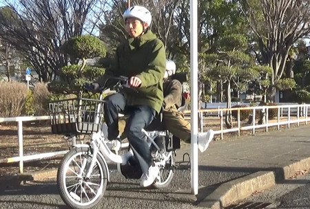 ダミー人形を使い、自転車の後部座席に乗った子どもの脚が柱に接触する事故を再現した様子（国民生活センター提供）