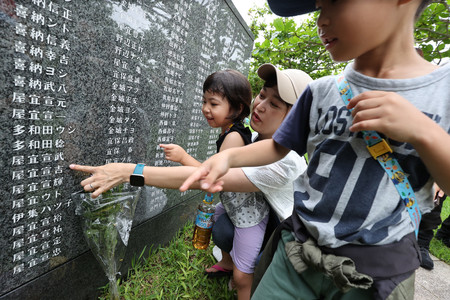 「平和の礎」を訪れ、高祖父の名前を指す子どもら＝２３日、沖縄県糸満市の平和祈念公園